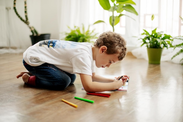 a little boy draws lying on the floor having fun happy childhood positive emotions side view