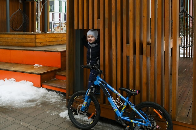 スノースーツを着た小さな男の子が自転車で遊び場へ行った