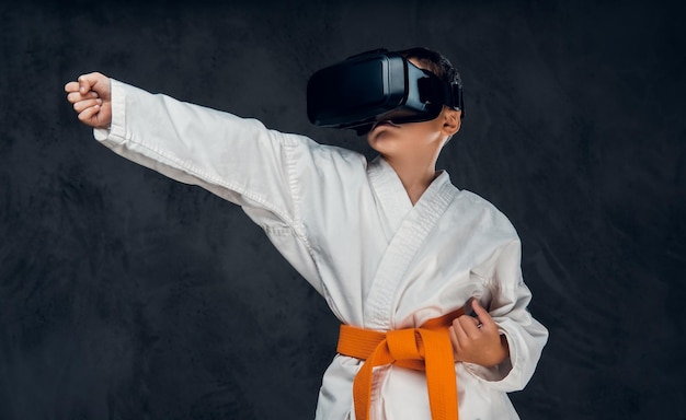 Little boy dressed in a white kimono with VR glasses on his head.