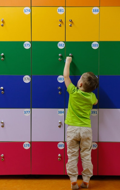 Little boy in dressing room near personal multicolored lockers.  cute  boy open locker in a locker room back view