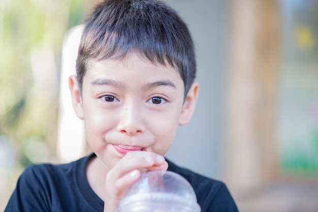 Little boy drinking cold blended milk soft drink by using straw