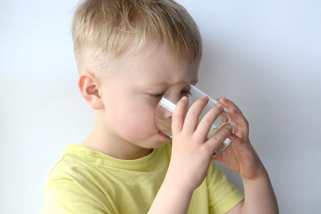 little boy drinks water from a glass