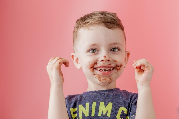 チョコレートを食べる少年 口の周りにチョコレートを塗ったかわいい幸せな少年 子供のコンセプト