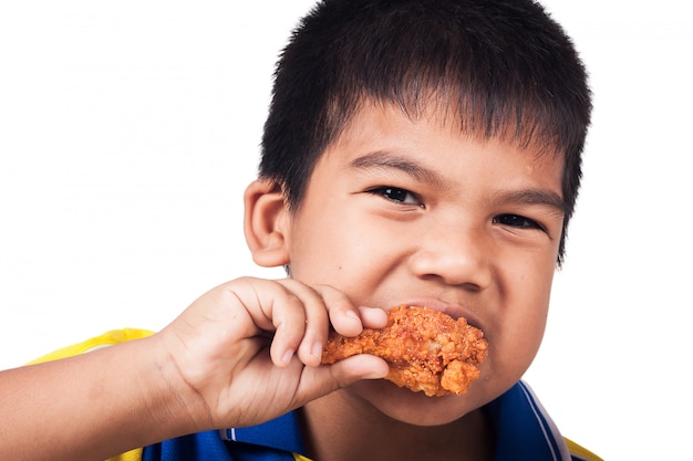 フライドチキンを食べる小さな男の子の背景を分離します。