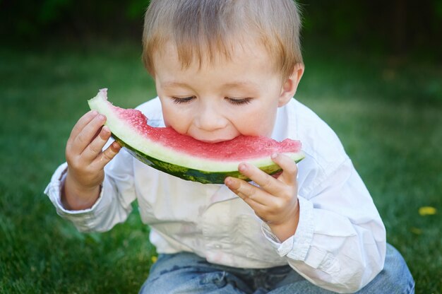 Little boy eating watermelon in the summer garden