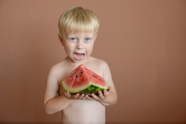 маленький мальчик ест арбуз