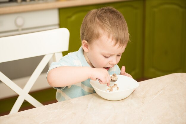 Little boy eats porridge.