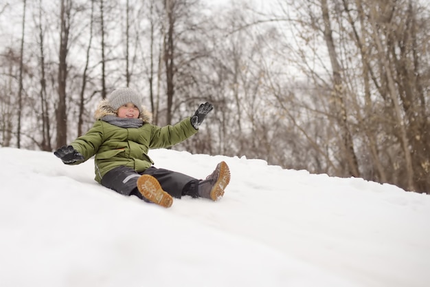 Little boy enjoy riding on ice slide in winter