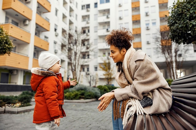 A little boy explaining to his babysitter something while gesturing and standing outdoors