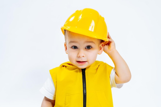 Фото Маленький мальчик исследует строительную площадку со своей желтой шапкой маленький мальчик в желтой шапке