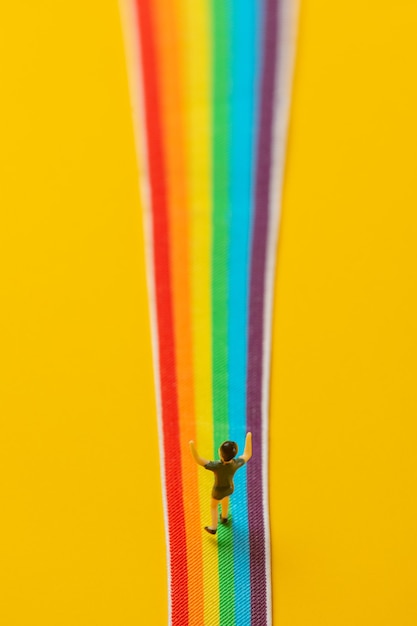 Фигурка маленького мальчика стоит на радужной ЛГБТ-полосе