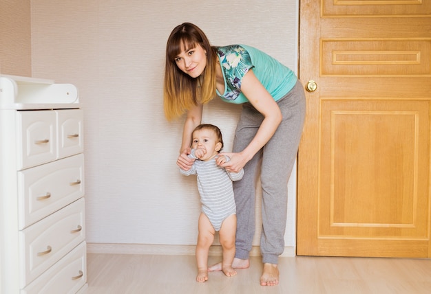 小さな男の子は母親の助けを借りて最初の一歩を踏み出します