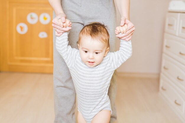 Little boy first steps with the help of mother