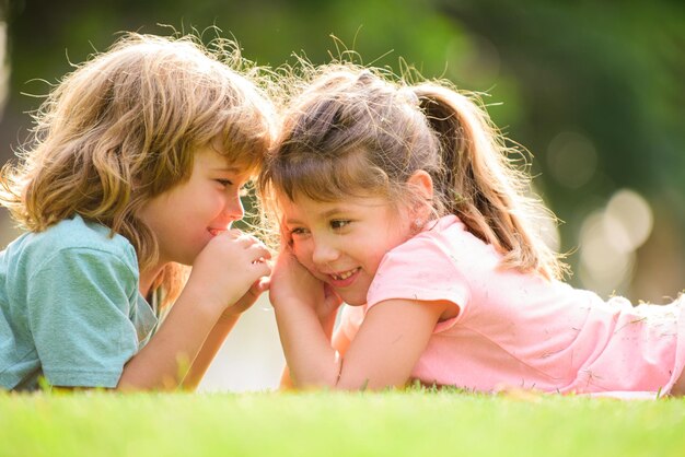 小さな男の子と女の子の親友が夏の公園で愛を込めてキスをしている子供たちを抱き締める小さな金