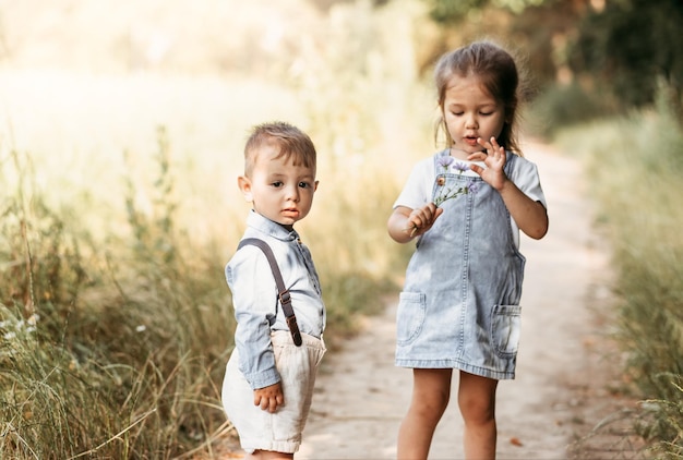 Little boy and girl children walking through the park Portrait of happy kids on a bright sunny day Friendship Summer holidays