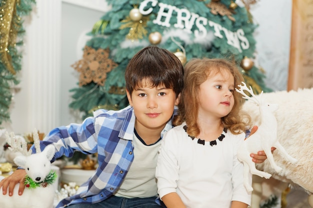 Little boy and girl among Christmas decorations