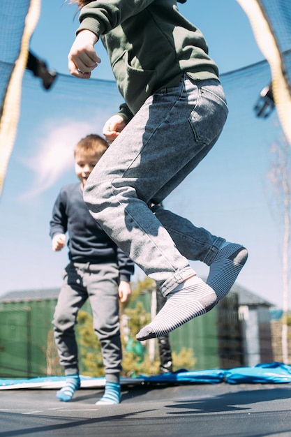 Little boy and girl jumping in trampoline in park Children's leisure cooutdoors lifestyle concept