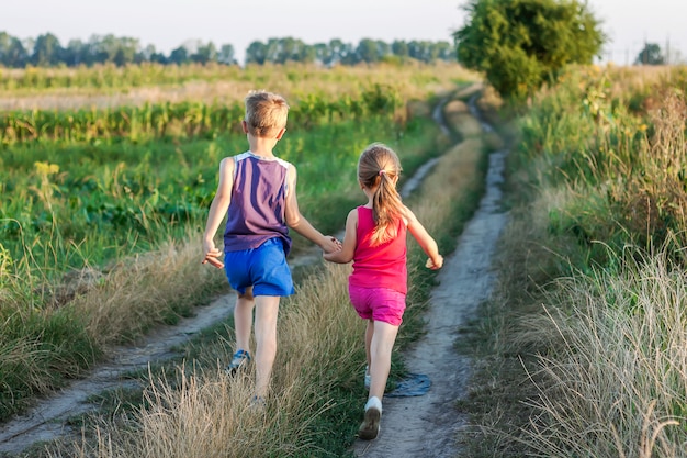 Little boy and girl running on a field road