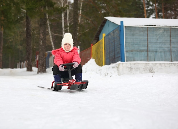 小さな男の子と女の子がそりで雪の丘から滑り降りる