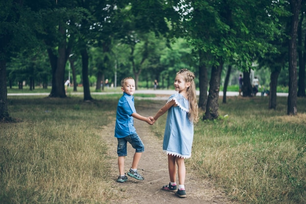 小さな男の子と女の子が一緒に歩いて、お互いの手を握って