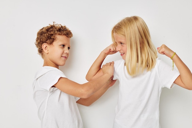 Little boy and girl in white Tshirts are standing next to isolated background