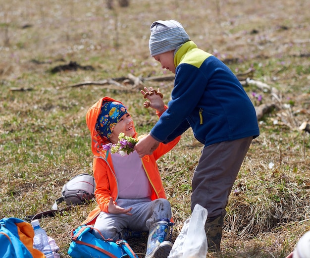 Little boy gives girl bouquet of wild flowers Hiking outdoor portrait