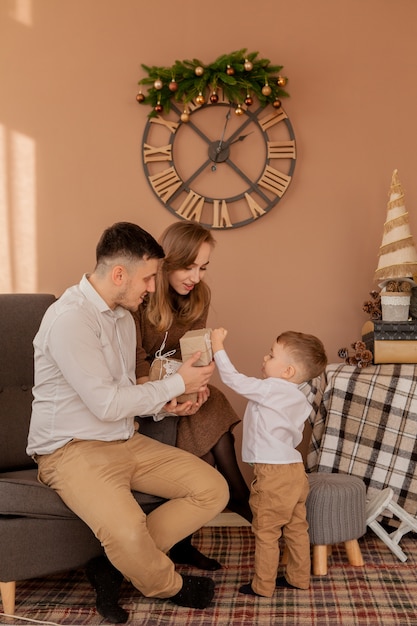 Little boy gives parents a gift box. Birthday gifts . Little son with his family.