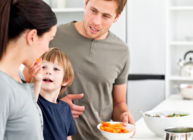 Ragazzino che dà a sua madre una carota mentre prepara il pranzo