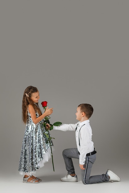 Little boy giving a red rose to child girl