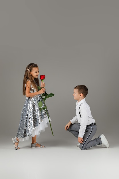 Little boy giving a red rose to child girl