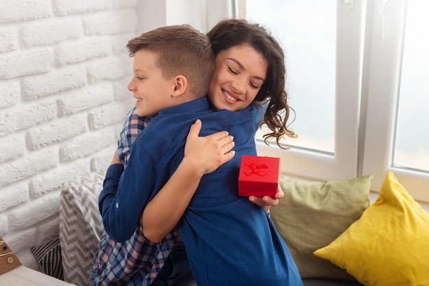 Ragazzino che fa un regalo a sorpresa e lo regala alla madre nel suo giorno speciale come la festa della mamma