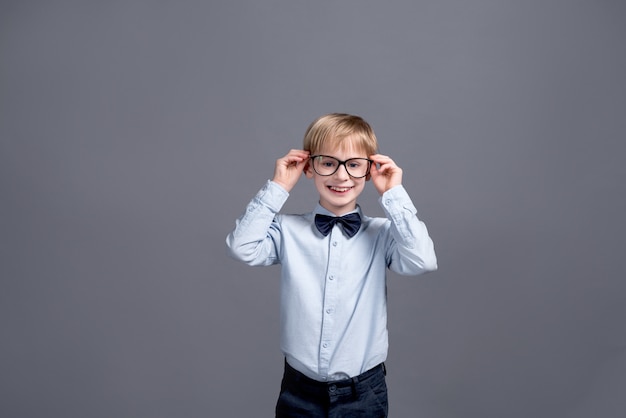 Little boy in glasses posing on grey