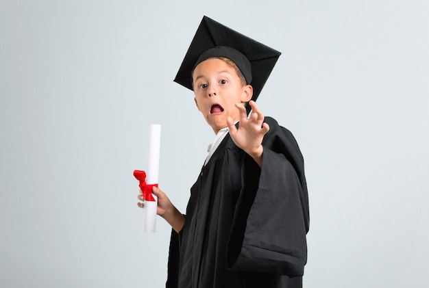 Photo little boy graduating is a little bit nervous and scared on grey background