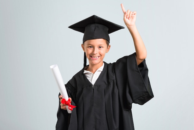 Little boy graduating standing and thinking an idea on grey background