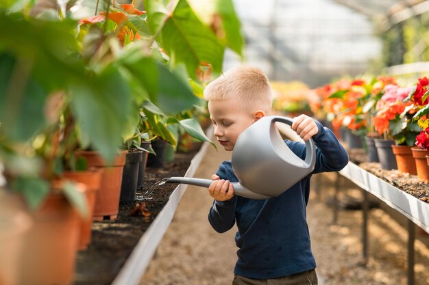 Little boy in greenhouse watering flowers