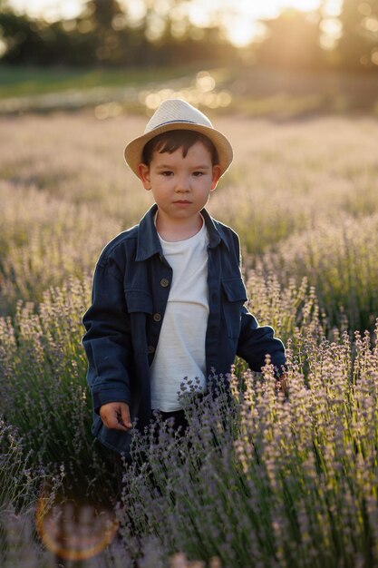 Little boy in hat walking on a lavender field