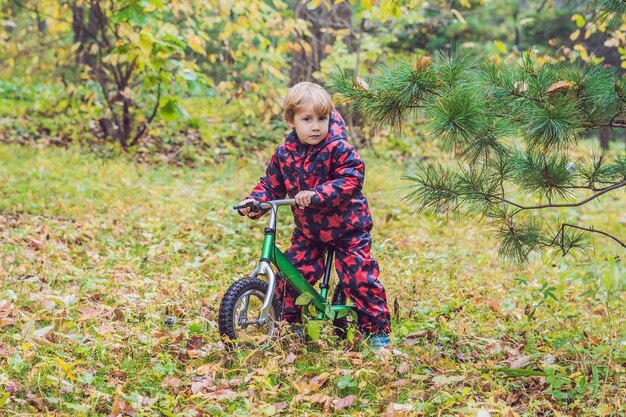 Little boy having fun on bikes in autumn forest. Selective focus on boy