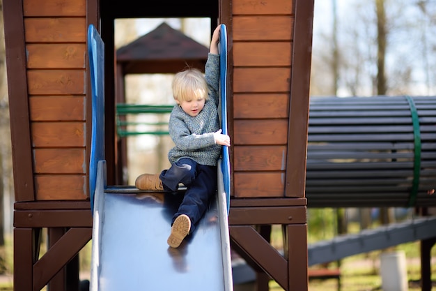 Ragazzino divertendosi nel parco giochi all'aperto / sulla diapositiva