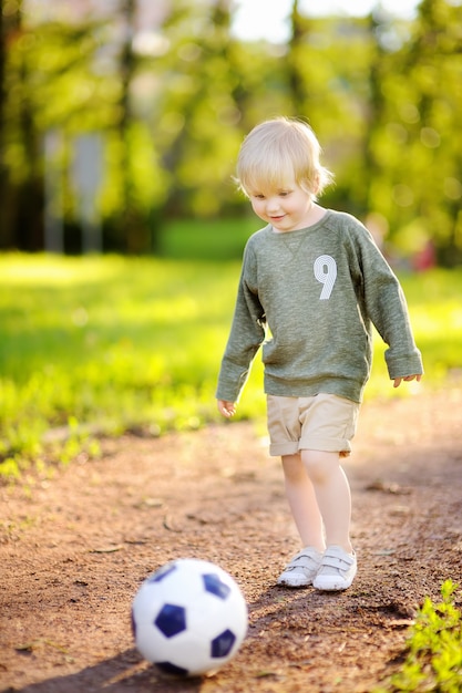 楽しんで晴れた夏の日にサッカーの試合をしている少年