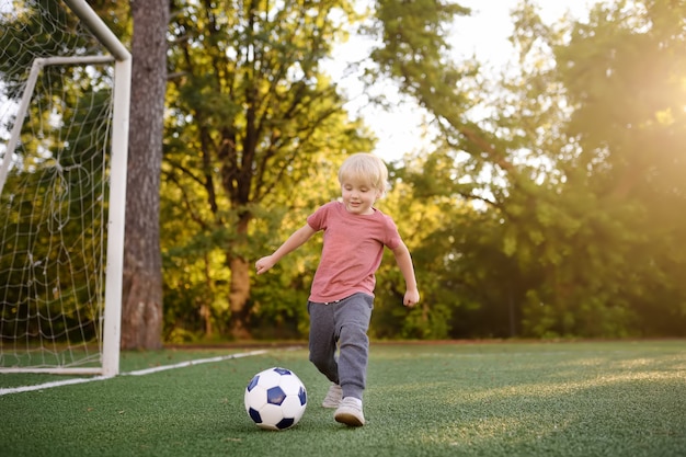 Ragazzino divertendosi giocando un calcio / partita di football americano il giorno di estate.