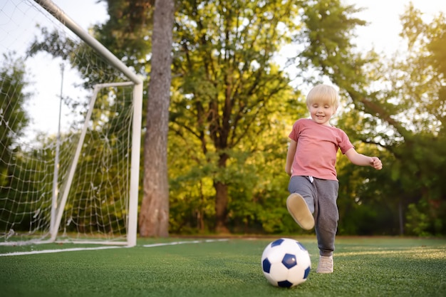 Little boy having fun playing a soccer/football game on summer day. 