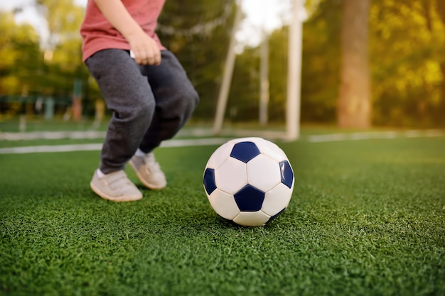 Little boy having fun playing a soccer/football game on summer day. 