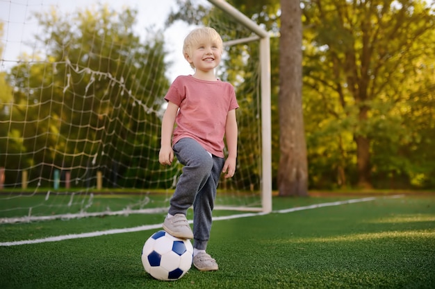 Little boy having fun playing a soccer/football game on summer day. 