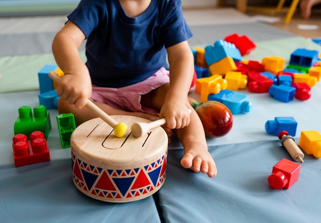 楽しんで、木のおもちゃのドラムを弾く少年