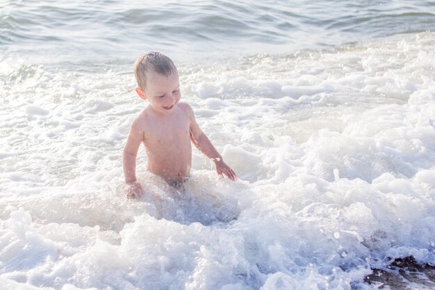Маленький мальчик веселится в море на волнах