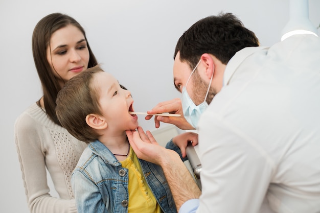 Ragazzino che fa esaminare la sua gola dal professionista della salute