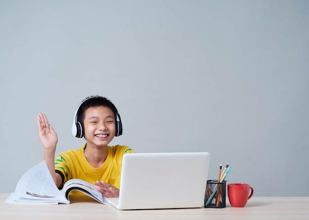 Little boy in headphones studying online using laptop