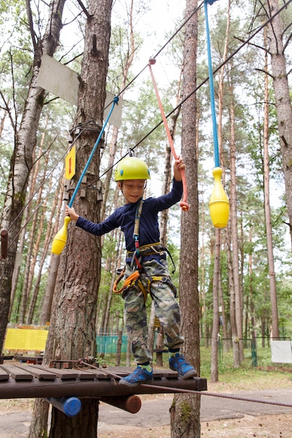 Ragazzino in casco trascorrere il tempo libero nel parco giochi di avventura.