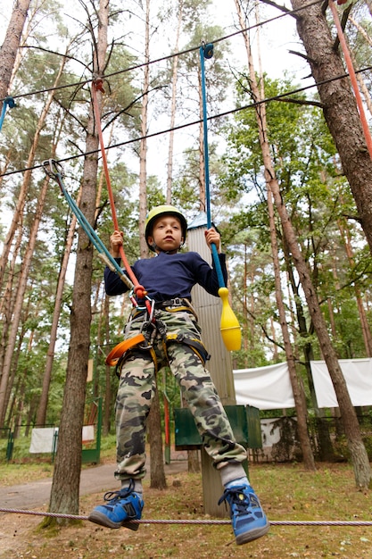 Little boy in helmet spend his leisure time in adventure\
playground.