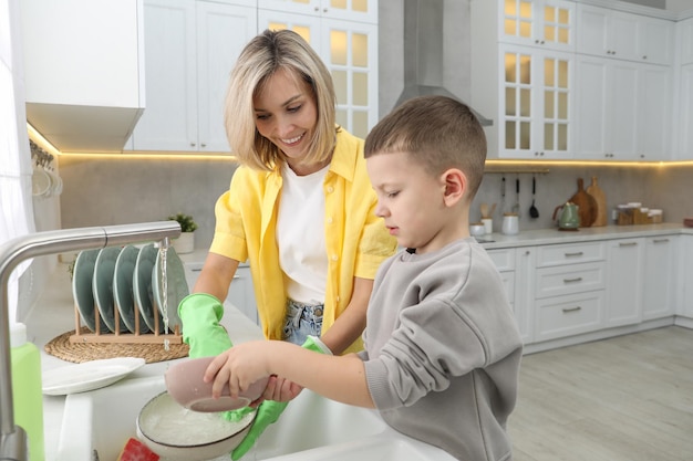 Little boy helping his mother washing dishes at home